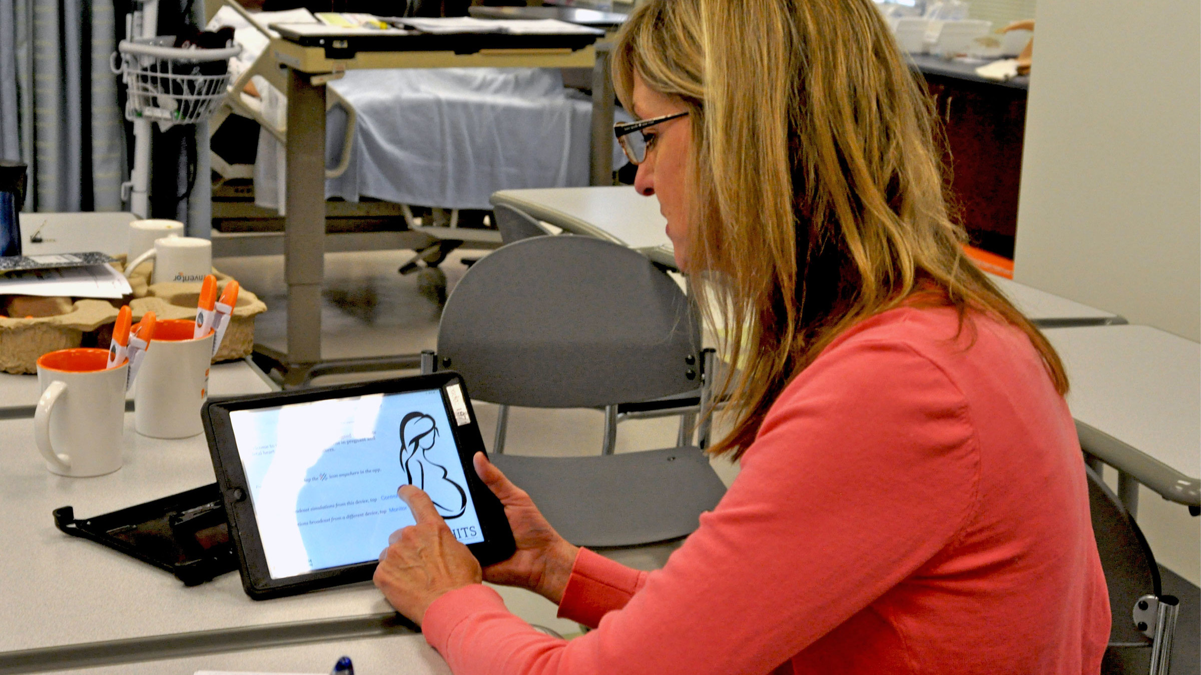 Susan Fancher gestures on a touchscreen tablet in a hospital room