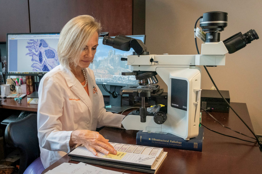 Debra Miller working at a microscope in her office