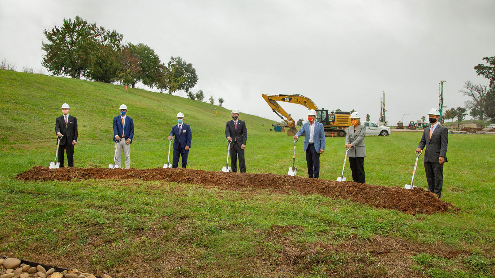 Seven people in hardhats pose with shovels in a groundbreaking event at Cherokee Farm