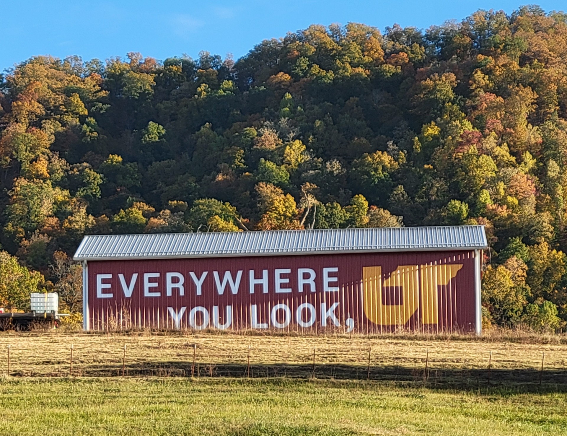 Orange and white Everywhere You Look, UT logo painted on red metal barn