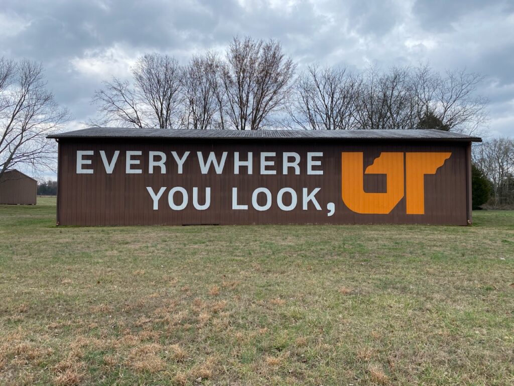 Orange and white "Everywhere You Look, UT" mural painted on brown barn